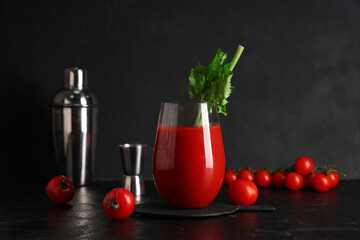 Glass of bloody mary with celery and tomatoes on black grunge background