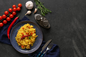 Plate with tasty pilaf and ingredients on black background