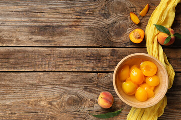 Composition with tasty canned peaches and napkin on wooden background