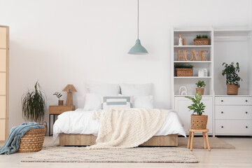 Fototapeta premium Interior of bedroom with plants in wicker baskets and closet