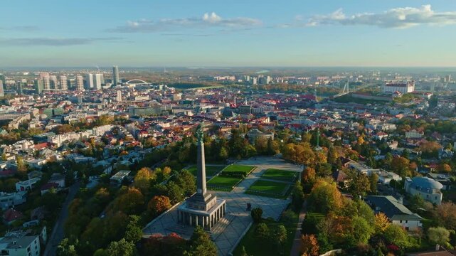 Aerial view of Bratislava, Slovakia at sunrise featuring the iconic Slavin monument, Bratislava Castle, and the city&rsquo;s skyline with autumn trees and modern buildings.