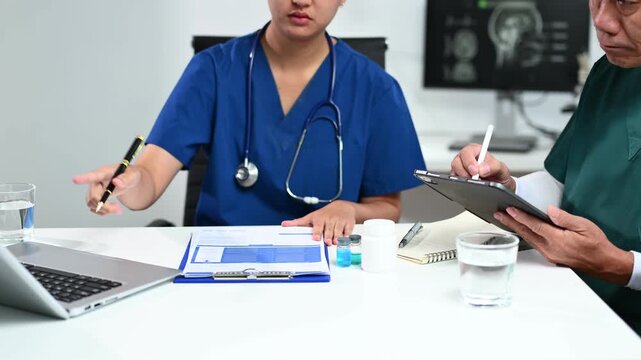 Healthcare team in scrubs consulting with medicine bottles, reports, and technology, showing real people collaboration in modern medical practice.