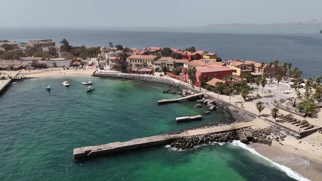 Drone aerial of Gor&eacute;e Island pier and colorful colonial houses along the waterfront in Senegal, UNESCO heritage site symbol of African history.