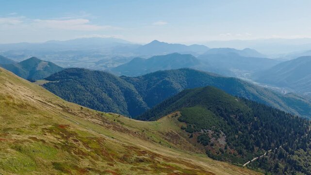 Drone shot from Chleb peak in the Mal&aacute; Fatra mountains, Slovakia, capturing rolling forested hills, mountain ridges, and distant valleys under a clear blue sky. (4K)