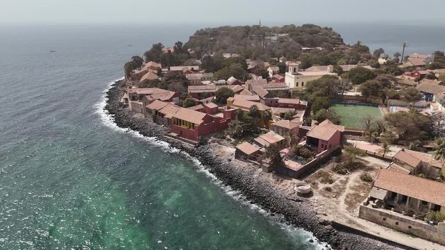 Wide aerial view of Gor&eacute;e Island by drone, showing colonial buildings, shoreline and turquoise waters of the Atlantic Ocean in Senegal, Africa