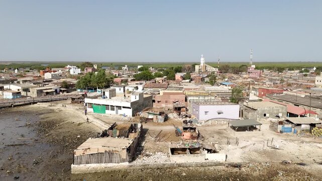 Drone aerial of Joal Fadiouth village in Senegal, showing traditional houses, coastline and daily life near the famous shell island cemetery.