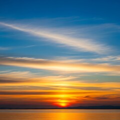 Obraz premium A breathtaking sunset over a tranquil body of water, showcasing a vibrant array of warm colors across a beautiful sky filled with layered clouds.