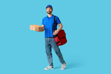Male courier with pizza boxes on blue background