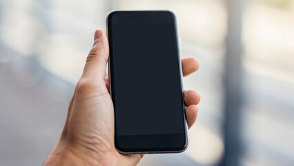 A person holding a smartphone with a blank screen, set against a blurred background, suggesting communication or technology themes.