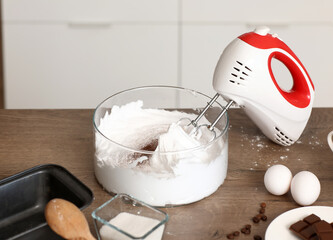 Mixer with whipped egg albumen on table in kitchen, closeup