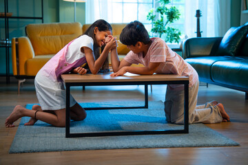 Asian siblings kids enjoying panja arm wrestling together at home in playful lifestyle moment