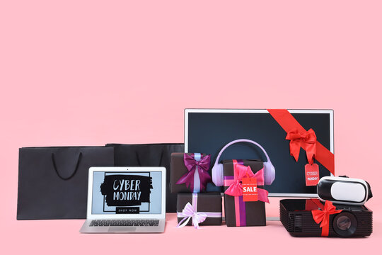 Laptop with text CYBER MONDAY, gifts and gadgets on pink background - Powered by Adobe