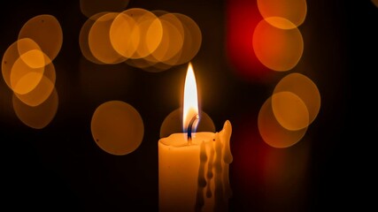 Softly flickering candlelight provides a warm, tranquil glow against a blurred backdrop of golden bokeh lights