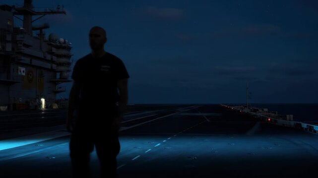 One person, a man, walking on aircraft carrier at night, navy, sea, in uniform.