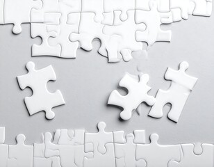 White puzzle pieces scattered on a light gray surface
