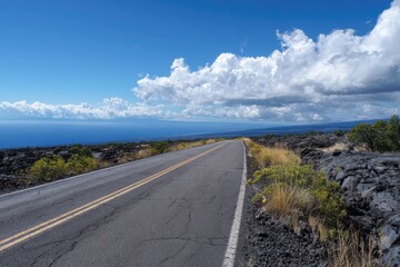 Open road leading to the ocean under a partly cloudy sky
