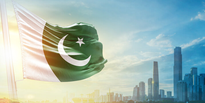 Pakistan flag wavering in beautiful clouds with building skyline. The flag with drone shot in beautiful sky. Pakistan national flag for independence day.