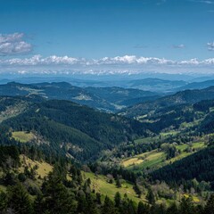 Fototapeta premium Panoramic mountain vista, showcasing rolling hills, valleys, and forests. A clear blue sky with scattered white clouds. Distant snow-capped peaks