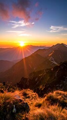 Sunrise/sunset over a mountain range.  Golden light beams down on a ridgeline.  Rocky, grassy terrain.  Vibrant colors