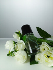 Picture of a bottle of perfume on a bucket of  artificial white rose flower. This photo can be used for promotion of clean life or advertising a scent of perfume
