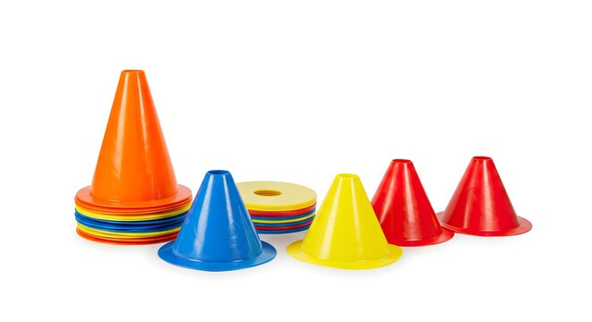 Assortment of colorful plastic cones flat discs arranged on a white surface casting soft shadows evoking sports training