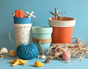 Artsy seaside display. Clay pots, yarn, seashells, and starfish sit against a blue backdrop evoking a nautical, summery, and crafted aesthetic