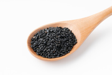 白背景にスプーンに載せた黒ごま（生ごま）のクローズアップ