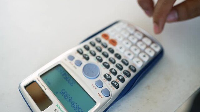 Hands Using Scientific Calculator on White Surface, Close-up of hands using a scientific calculator on a white surface