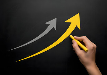 Hand drawing a yellow upward arrow on a black background, representing growth, progress, and success in business