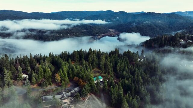 Aerial drone view above the clouds with forest hills, rivers, and houses in Washington State USA