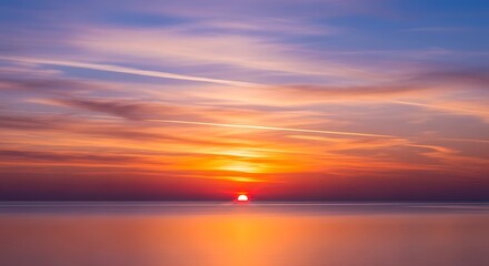 Fototapeta premium A breathtaking sunset paints the tranquil ocean with vibrant hues of orange, pink, and purple.