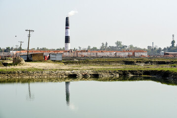 Industrial Construction Site With Tall Chimneys Reflected In Calm River Waters During Daytime