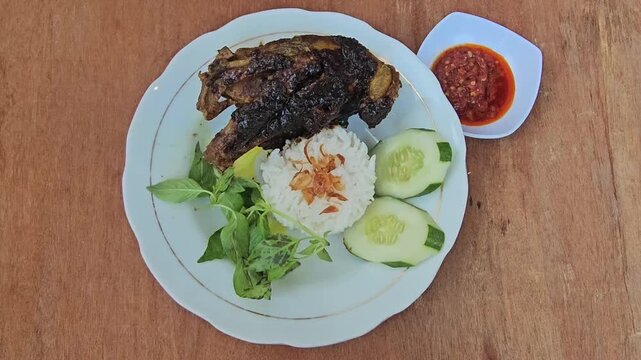 rice with chicken,Nasi bebek madura,Fried duck or Roasted duck with black sauce topping served with rice,fresh vegetables and sambal or chili sauce,traditional dish from Maduranese in Madura island Ea
