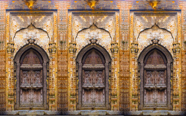 A beautiful old wooden door on stone wall background, old entrance wooden double-leaf brown door with wrought iron decor, old door building exterior detail