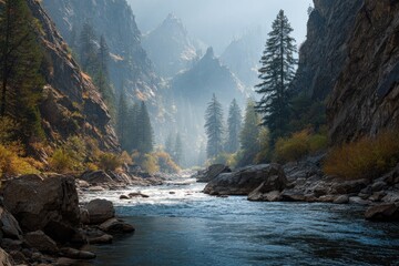 Serene river flows through a misty mountain canyon, sunlight illuminating the towering rock faces and evergreens along its banks
