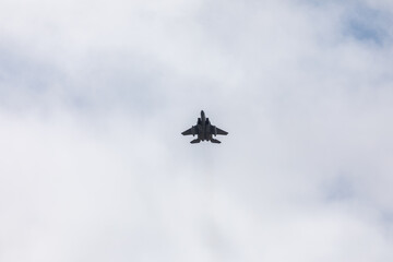 A powerful American twin-engine fighter jet flying in the sky during an air show event, demonstrating military aviation speed, agility, and maneuverability against the clouds, captured in Oregon, USA