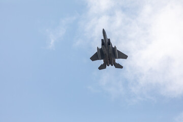 A powerful American twin-engine fighter jet flying in the sky during an air show event, demonstrating military aviation speed, agility, and maneuverability against the clouds, captured in Oregon, USA