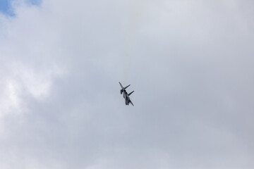 A powerful American twin-engine fighter jet flying in the sky during an air show event, demonstrating military aviation speed, agility, and maneuverability against the clouds, captured in Oregon, USA