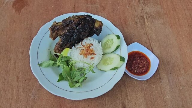 rice with chicken,Nasi bebek madura,Fried duck or Roasted duck with black sauce topping served with rice,fresh vegetables and sambal or chili sauce,traditional dish from Maduranese in Madura island Ea