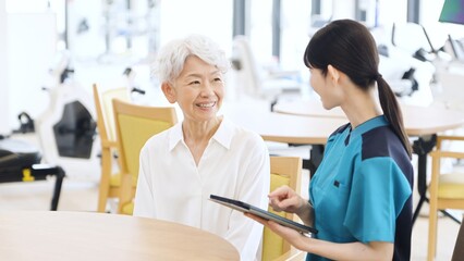 タブレットで健康チェックをするアジア人介護士
