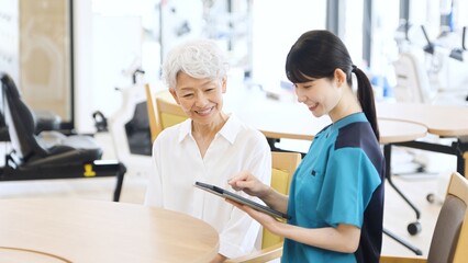タブレットで健康チェックをするアジア人介護士 © mapo