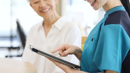 タブレットで健康チェックをするアジア人介護士