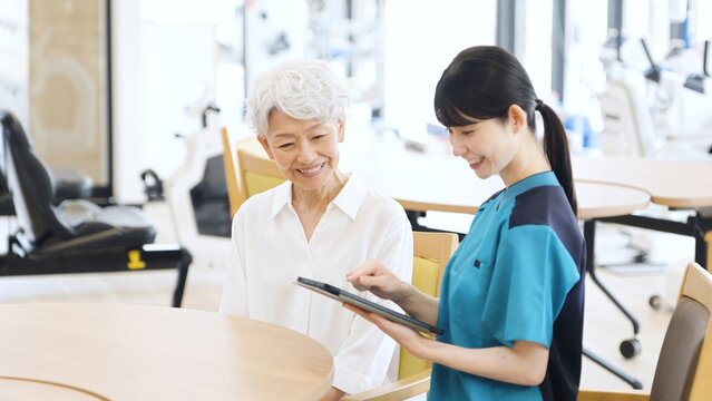 タブレットで健康チェックをするアジア人介護士