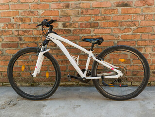 A white bike leaning against a brick wall
