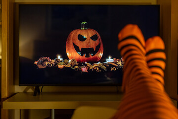 Halloween streaming indoors with striped socks, pumpkin decor and cozy autumn atmosphere perfect...