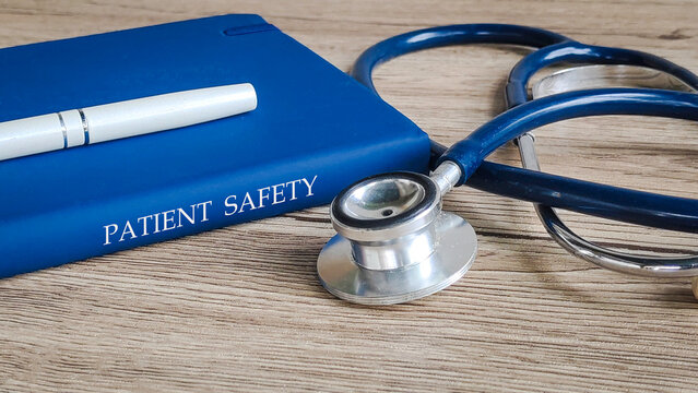 A pen and stethoscope on a book titled "PATIENT SAFETY," representing healthcare standards and quality.