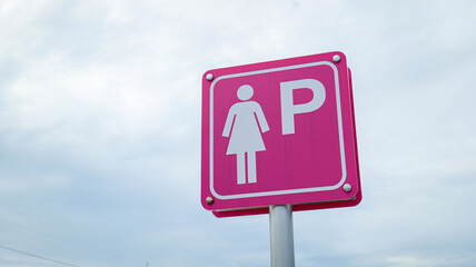 Red sign with white female icon and letter P indicating dedicated women&rsquo;s parking space, symbolizing safety, accessibility, respect, and convenience in urban transportation facilities.
