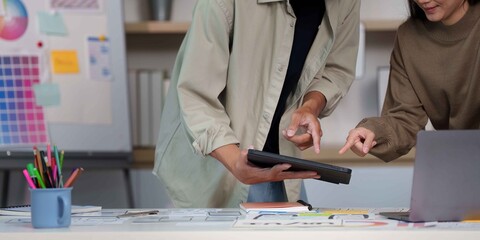 Innovative Collaboration. Young professionals analyzing project data on tablet.