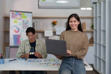 Obraz premium UI UX Design Team. Young woman smiling while holding laptop in modern creative office.