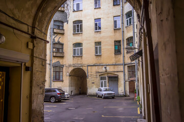Panorama of famous well courtyards in Saint Petersburg, Russia, with arched passages, parked cars, and weathered facades.
